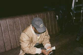 Asake counting cash in a Guess cap during the M$NEY era