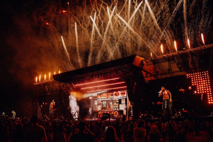 Burna Boy performing live on stage with fireworks and crowd