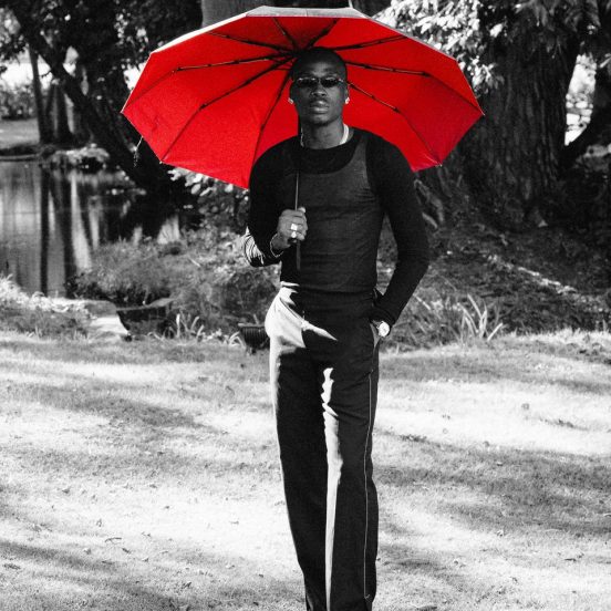 Fireboy DML holding a red umbrella in a black-and-white ZUKO! promo