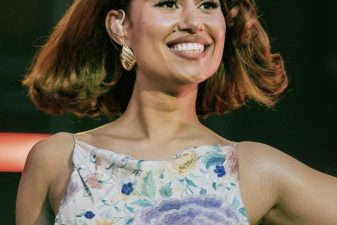 RAYE performing in a floral dress on stage