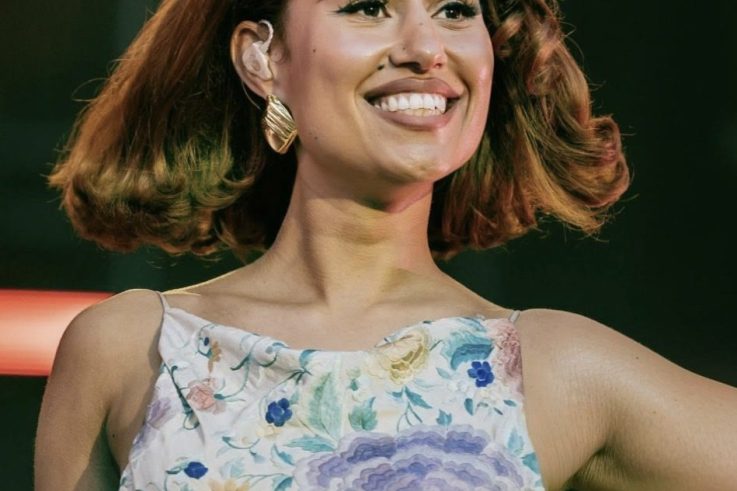 RAYE performing in a floral dress on stage