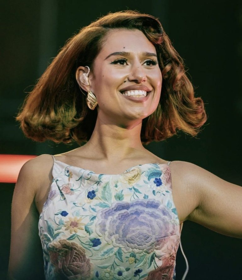 RAYE performing in a floral dress on stage