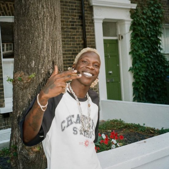 Seyi Vibez smiling outdoors in a Chase Studio shirt