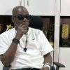 Headies founder Ayo Animashaun seated in his office in front of award trophies.