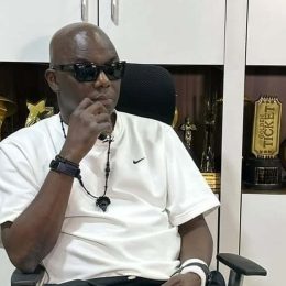 Headies founder Ayo Animashaun seated in his office in front of award trophies.