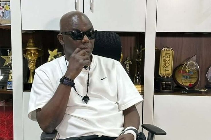 Headies founder Ayo Animashaun seated in his office in front of award trophies.