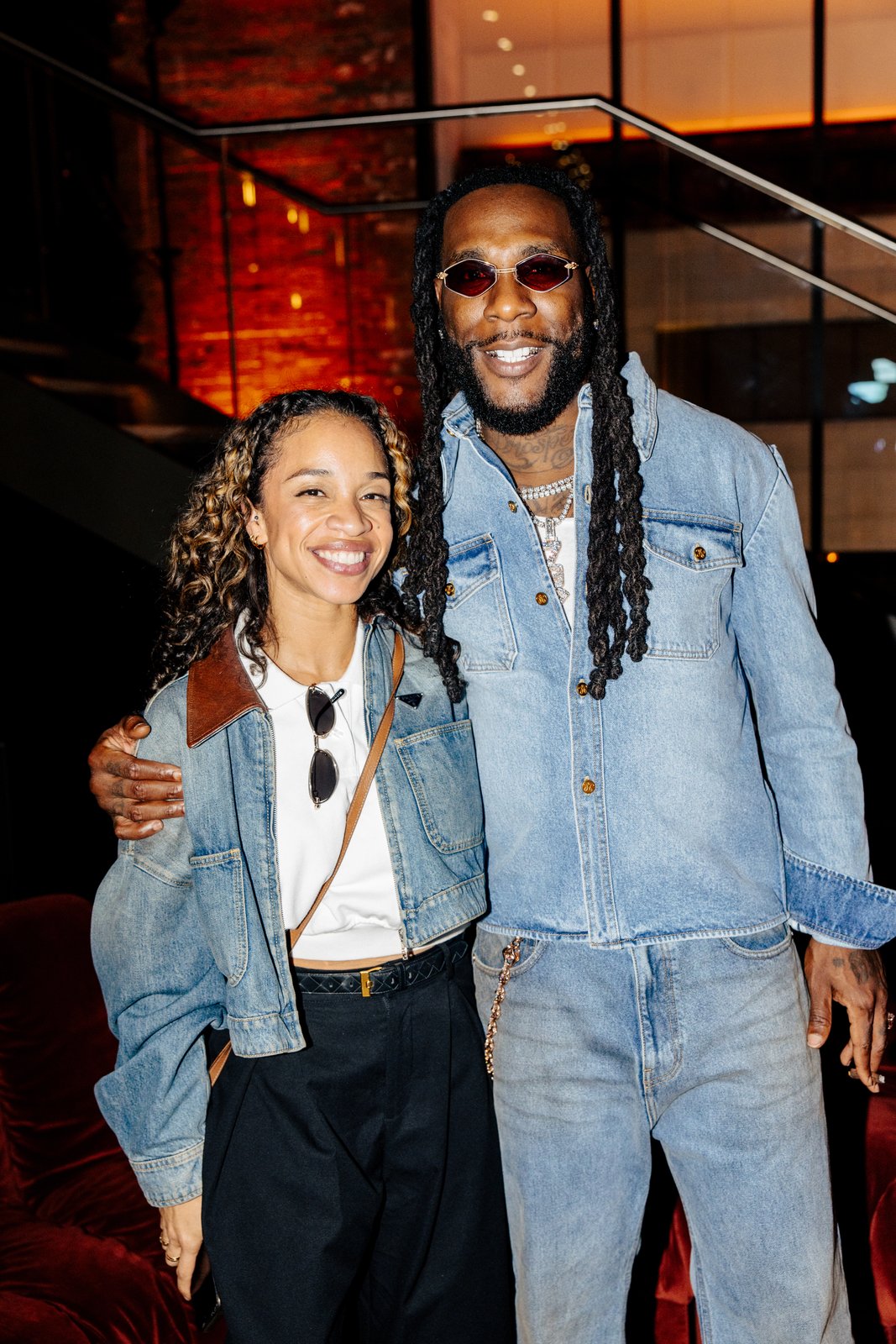 Burna Boy in double denim and tinted sunglasses posing with a guest at the Apple Music x Beats after-party in London
