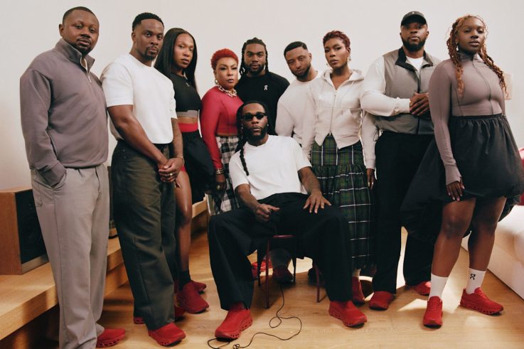 Burna Boy seated in red On sneakers with his family and team for his first On collection.