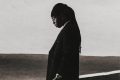 FOLA "9" album cover: FOLA in a dark suit with his head bowed against a pale sky, a gothic "9" in the corner.