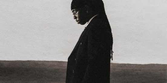 FOLA "9" album cover: FOLA in a dark suit with his head bowed against a pale sky, a gothic "9" in the corner.