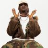 Magicsticks in a camouflage jacket and cream cap, hands raised